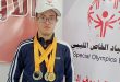 السباح عبد الهادي الرطيب يرتدي عدة ميداليات رياضية أمام لوحة تحمل شعار الأولمبياد الخاص الليبي.