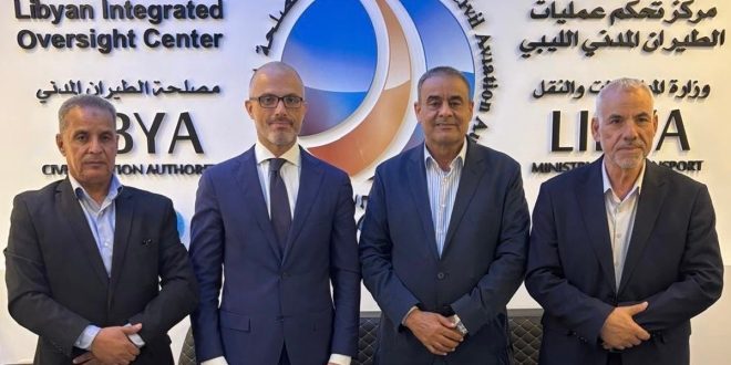 صورة جماعية تضم سفير الاتحاد الأوروبي لدى ليبيا نيكولا أورلاندو، ووزير المواصلات محمد الشهوبي، ورئيس مصلحة الطيران المدني محمد عبدالسلام شليبك، ومسؤولاً آخر، يقفون داخل مركز الرقابة المتكاملة الجديد لقطاع الطيران المدني الليبي في طرابلس، وتظهر خلفهم شعارات مصلحة الطيران المدني ووزارة المواصلات
