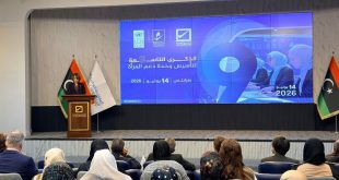 قاعة مؤتمرات تضم حضورًا من الرجال والنساء يجلسون أمام منصة تتحدث عليها امرأة، وخلفها شاشة كبيرة تعرض شعار الذكرى التاسعة لتأسيس وحدة دعم المرأة في طرابلس بتاريخ 14 يونيو 2026، إلى جانب أعلام ليبيا وشعارات الجهات المنظمة.