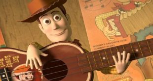 لقطة قريبة للشخصية الكرتونية "وودي" من فيلم Toy Story 5 يبتسم وهو يمسك بجيتار خشبي
