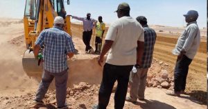 عمال وفنيون يتابعون أعمال صيانة وإصلاح مسار كابل الألياف البصرية المتضرر في منطقة صحراوية بين تازربو والكفرة