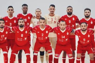 ​لقطة جماعية للاعبي فريق الاتحاد الليبي لكرة القدم داخل الصالات، يظهر فيها اللاعبون في صفين وهم يرتدون الطاقم الأساسي باللونين الأحمر والأبيض ويقفون بوضعية الاستعداد لالتقاط الصورة الرسمية