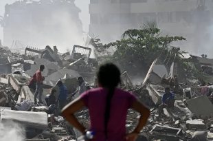 ​امرأة تنظر إلى ركام مبانٍ منهارة وأشخاص يبحثون بين الأنقاض وسط تصاعد الغبار بعد زلزال فنزويلا المدمر.