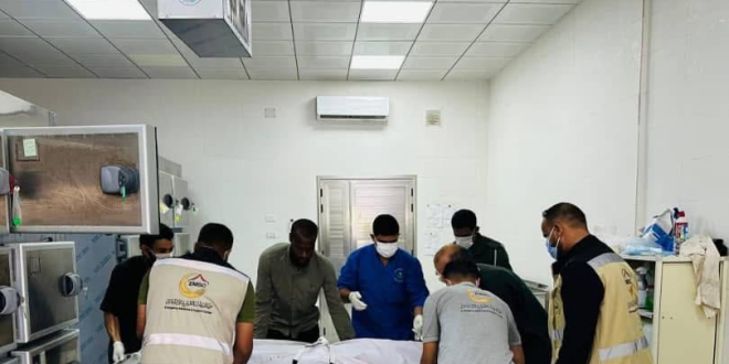 عناصر مركز طب الطوارئ والدعم في ليبيا أثناء نقل جثمان على محفة داخل ثلاجة الموتى.