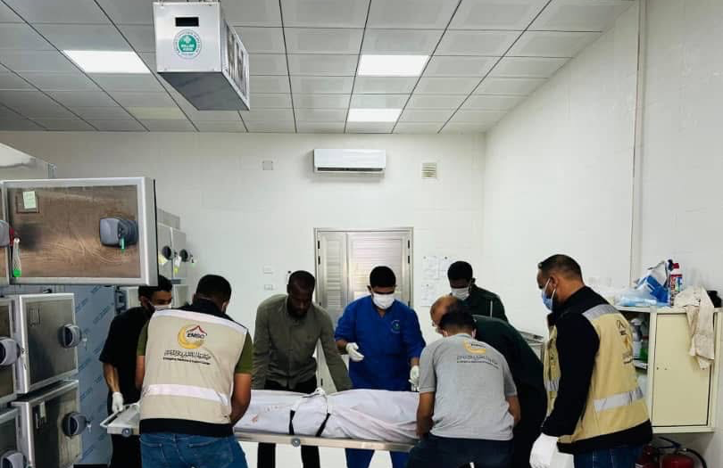 عناصر مركز طب الطوارئ والدعم في ليبيا أثناء نقل جثمان على محفة داخل ثلاجة الموتى.