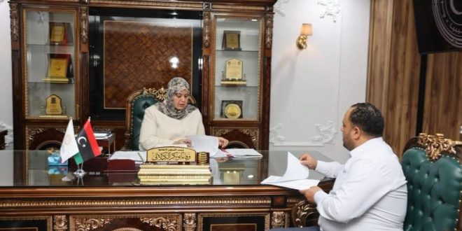 وزيرة الشؤون الاجتماعية وفاء الكيلاني تجلس في مكتبها وتراجع أوراقاً رسمية خلال اجتماع مع مدير إدارة منحة الزوجة والأولاد.