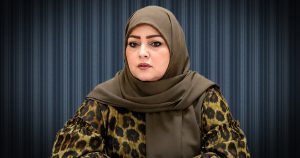 النص: لقطة بورتريه لمديرة إدارة شؤون ذوي الإعاقة بالهيئة العامة لصندوق التضامن الاجتماعي، جميلة شقلابو، ترتدي حجاباً زيتوني اللون وفستاناً بنقشة النمر، وتتحدث خلف خلفية مخططة باللون الرمادي الداكن.