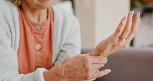 لقطة قريبة لامرأة مسنة تمسك بمعصم يدها وتبدو عليها علامات الألم أو الضعف في المفاصل والعظام،