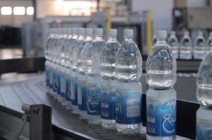 لقطة قريبة لخط إنتاج مياه "النبع" في قصر بن غشير، تظهر زجاجات مياه بلاستيكية معبأة تحمل الشعار