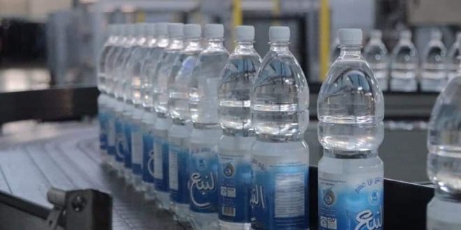لقطة قريبة لخط إنتاج مياه "النبع" في قصر بن غشير، تظهر زجاجات مياه بلاستيكية معبأة تحمل الشعار