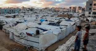 لقطة علوية لمخيم شاسع ومزدحم للنازحين في قطاع غزة، مليء بصفوف من الخيام القماشية والبلاستيكية البيضاء والرمادية المتهالكة،