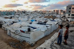 لقطة علوية لمخيم شاسع ومزدحم للنازحين في قطاع غزة، مليء بصفوف من الخيام القماشية والبلاستيكية البيضاء والرمادية المتهالكة،
