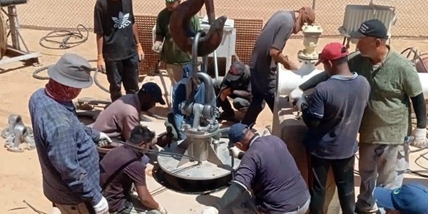 فنيو وعمال جهاز مشروع النهر الصناعي يعملون على تركيب وتجهيز مضخة مياه جديدة في أحد حقول الآبار