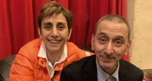صورة تجمع المخرجة ريما الرحباني وشقيقها الفنان زياد الرحباني يبتسمان أمام خلفية ستارة حمراء.