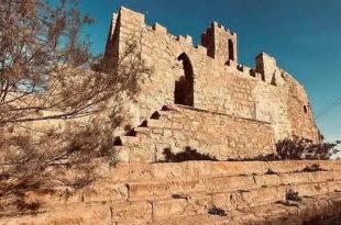 ​صورة فوتوغرافية تظهر بقايا قلعة تاريخية مهدمة جزئياً ومبنية من الحجر الرملي على هضبة مرتفعة في ليبيا.