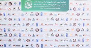 ​لوحة خلفية بيضاء كبيرة خاصة بالملتقى البيئي الأول في طرابلس، يظهر في أعلاها لافتة خضراء مكتوب عليها باللغتين العربية والإنجليزية "المؤتمر الدولي الأول لإدارة الملوثات البيئية والنفايات الخطرة في ليبيا"، وتتكرر على بقية اللوحة شعارات الجهات المشاركة والمنظمة بشكل منتظم.