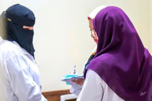 ثلاث طبيبات أو أخصائيات يرتدين معاطف طبية بيضاء يتشاورن معاً ويمسكن بملف طبي، أثناء زيارة طبية لمركز الأندلس لتأهيل وعلاج ذوي الإعاقة.