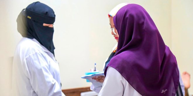 ثلاث طبيبات أو أخصائيات يرتدين معاطف طبية بيضاء يتشاورن معاً ويمسكن بملف طبي، أثناء زيارة طبية لمركز الأندلس لتأهيل وعلاج ذوي الإعاقة.