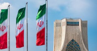 أعلام إيرانية ترفرف بجانب برج آزادی في طهران تحت سماء صافية