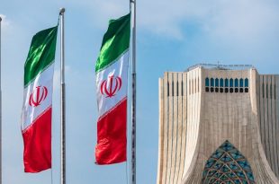 أعلام إيرانية ترفرف بجانب برج آزادی في طهران تحت سماء صافية