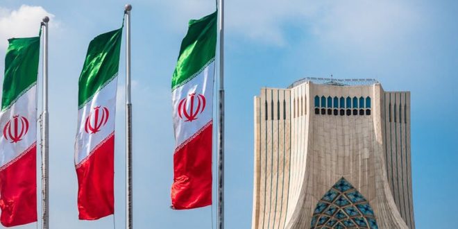 أعلام إيرانية ترفرف بجانب برج آزادی في طهران تحت سماء صافية