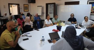 مجموعة من الصحفيين والإعلاميين الليبيين يشاركون في حلقة نقاشية أو ورشة عمل داخل قاعة اجتماعات، حيث يلتفون حول طاولة بيضاء كبيرة ويستمعون بتركيز لأحد المتحدثين، في بيئة عمل مهنية تجسد النقاشات حول واقع الصحافة والإعلام