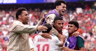 ​فرحة عارمة للاعبي المنتخب المغربي لكرة القدم، يظهر فيها اللاعب إبراهيم دياز بقميصه رقم 10 محتضناً زملاءه عز الدين أوناحي وسفيان رحيمي وبقية عناصر المنتخب أثناء الاحتفال بتأهلهم التاريخي في كأس العالم