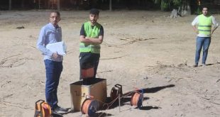​ثلاثة شبان (طلاب وأكاديميون) يقفون في منطقة ترابية مفتوحة بمحمية الزراعة أثناء إجراء مسح ميداني، يرتدي اثنان منهم سترات سلامة فسفورية، ويحمل أحدهم أوراقًا لتدوين البيانات، مع وجود معدات وأجهزة قياس جيوفيزيائية على الأرض