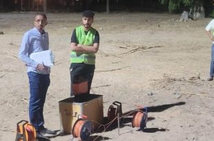 ​ثلاثة شبان (طلاب وأكاديميون) يقفون في منطقة ترابية مفتوحة بمحمية الزراعة أثناء إجراء مسح ميداني، يرتدي اثنان منهم سترات سلامة فسفورية، ويحمل أحدهم أوراقًا لتدوين البيانات، مع وجود معدات وأجهزة قياس جيوفيزيائية على الأرض