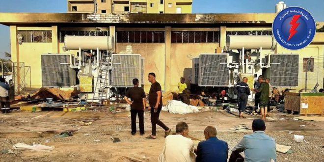 عنصر فني وعمال صيانة تابعة للشركة العامة للكهرباء يعملون على صيانة وتركيب ملحقات محولات كهربائية ضخمة أمام مبنى محطة جنوب الزاوية.