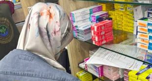 مفتشة من فريق الإصحاح البيئي ترتدي حجابًا منقوشًا وجاكيت جينز تفحص أرفف الأدوية والعلب الطبية داخل إحدى الصيدليات أثناء جولة تفتيشية