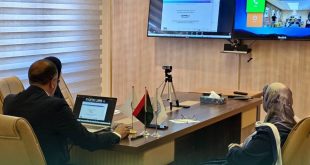 أمين عام اللجنة الوطنية للتربية والثقافة والعلوم حسين المشرقي ومسؤولون يجلسون حول طاولة اجتماعات بها أعلام صغيرة