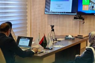 أمين عام اللجنة الوطنية للتربية والثقافة والعلوم حسين المشرقي ومسؤولون يجلسون حول طاولة اجتماعات بها أعلام صغيرة