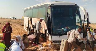 حافلة سياحية بيضاء متضررة إثر خروجها عن الطريق الصحراوي في منطقة النفاتية باتجاه بن قردان، وركاب وعناصر أمن وإنقاذ يقفون بجوار الحافلة بين الأمتعة على جانب الطريق
