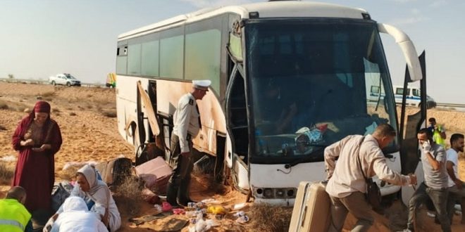 حافلة سياحية بيضاء متضررة إثر خروجها عن الطريق الصحراوي في منطقة النفاتية باتجاه بن قردان، وركاب وعناصر أمن وإنقاذ يقفون بجوار الحافلة بين الأمتعة على جانب الطريق