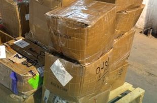 مجموعة من الطرود والكراتين البريدية المغلفة بالبلاستيك والمحملة على منصة خشبية داخل قسم الشحن بمطار معيتيقة الدولي