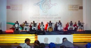 فرقة موسيقية شعبية تؤدي عرضاً حياً على خشبة المسرح خلف شعار المهرجان الوطني العاشر للفنون الشعبية والأغنية التراثية "تراثنا يجمعنا" بمدينة غريان.