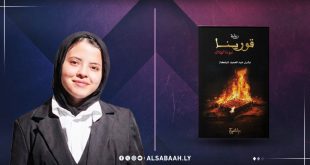 ​صورة شخصية للكاتبة الليبية بشرى شبلكة بابتسامة هادئة، وإلى جوارها غلاف روايتها "قورينا.. نبوءة الهلاك" الذي يحمل تصميماً يشتمل على عناصر نيران وتراث، على خلفية ذات ألوان أرجوانية مميزة لمنصة الصباح