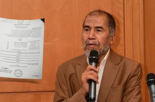 صورة لأخصائي المبيدات سالم الشبلي يتحدث عبر الميكروفون وإلى جانبه وثيقة قرار وزارة الزراعة بشأن المبيدات.