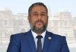 صورة شخصية رسمية للخبير الاقتصادي والمالي الليبي سامح الكانوني، بملامح جادة وسترة زرقاء داكنة، أمام خلفية باهتة لقصر الخلد في طرابلس. الصورة مخصصة لمنصة الصباح الإخبارية لتغطية تصريحاته حول أزمة سوق الصرف الليبي.