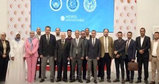 ​صورة جماعية للمشاركين والفرق الطبية الليبية والتركية في الملتقى الليبي التركي لزراعة الكبد بطرابلس أمام شاشة عرض تحمل شعار مستشفى ميديبول التركي.