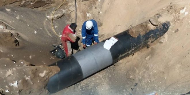 ​فريق فني من شركة الواحة للنفط يعالج تسرباً في خط أنبوب نفطي يربط بين الزقوط والسدرة داخل خندق محفور.