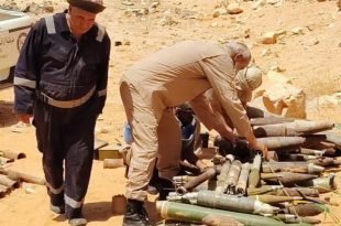 ​عناصر من هيئة السلامة الوطنية يعاينون كمية من مخلفات الحرب والذخائر غير المنفجرة في منطقة صحراوية بمدينة بني وليد تمهيداً لإتلافها.