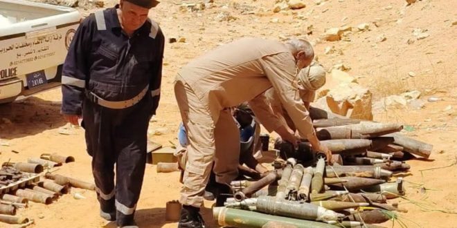 ​عناصر من هيئة السلامة الوطنية يعاينون كمية من مخلفات الحرب والذخائر غير المنفجرة في منطقة صحراوية بمدينة بني وليد تمهيداً لإتلافها.