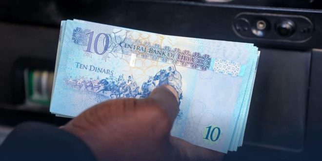 ​يد شخص تقوم بسحب أوراق نقدية ليبية فئة عشرة دنانير من جهاز صراف آلي تابع لمصرف الجمهورية.