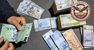 أيدٍ تقوم بعد حزم نقدية من الدينار الليبي والدولار الأمريكي، بجانب شعار جهاز مكافحة الجرائم المالية وغسل الأموال وتمويل الإرهاب الليبي.
