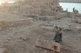 ​شخص يجمع المخلفات في أكياس سوداء بين الآثار الحجرية المطلة على البحر بمدينة سوسة ضمن مشروع تنظيف الآثار.
