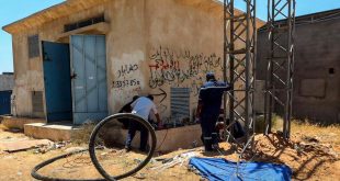 عمال صيانة تابعة للشركة العامة للكهرباء يعملون قرب غرفة محول وأبراج معدنية لإصلاح كوابل متضررة في منطقة أبابوسليم بطرابلس.