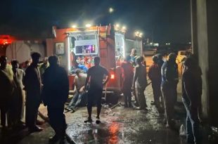​صورة ليلية لسيارة إطفاء وتجمهر لرجال الإطفاء والمواطنين أمام مخزن مواد الغذائية بعد السيطرة على حريق في طبرق.
