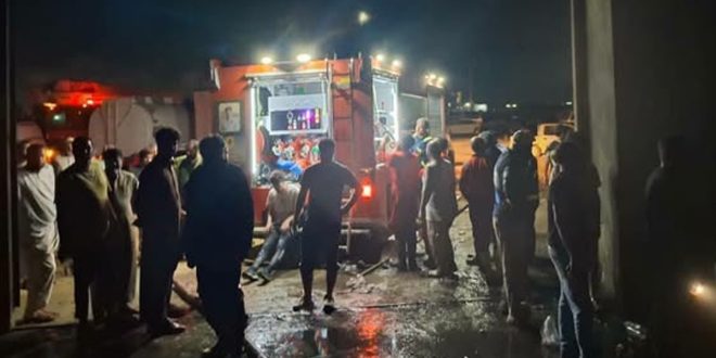 ​صورة ليلية لسيارة إطفاء وتجمهر لرجال الإطفاء والمواطنين أمام مخزن مواد الغذائية بعد السيطرة على حريق في طبرق.